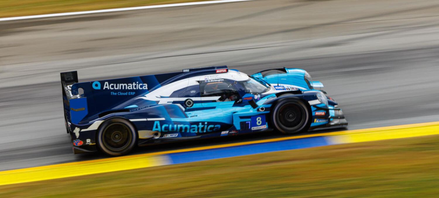 Acumatica | Image of a race car on a track with the Acumatica logo prominently displayed on the fin | Acro Commerce